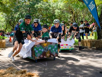 People pushing a couch with a young person on it