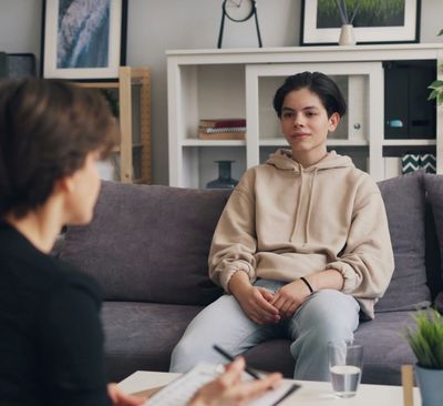 Young person sitting on a couch facing an older person